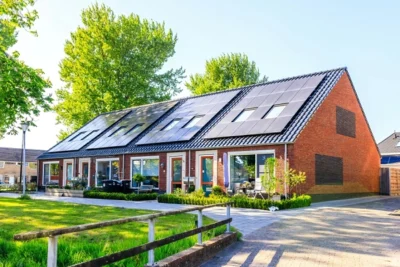 A residential home with solar panels installed on the roof, surrounded by green trees and a well-maintained garden, representing eco-friendly home improvements